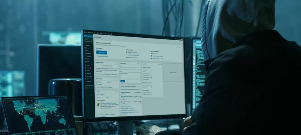 Person mit Kapuze mit 3 Bildschirmen vor sich. Bildschirme zeigen eine Weltkarte, ein Abschnitt mit Code und ein WordPress Dashboard.